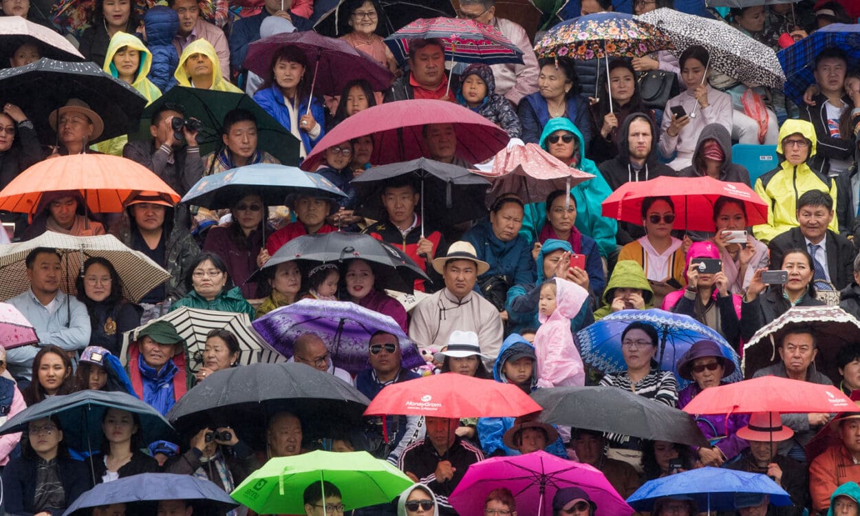 Image of a packed stadium crowd under umbrellas