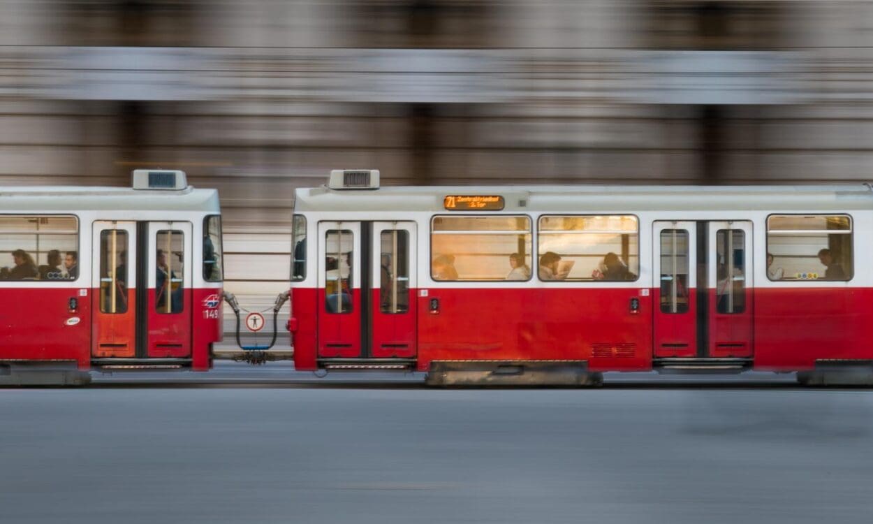 Red and white tram panned along a street in Vienna, Austria, background building facade blurred into horizontal streaks while the tram stays sharp