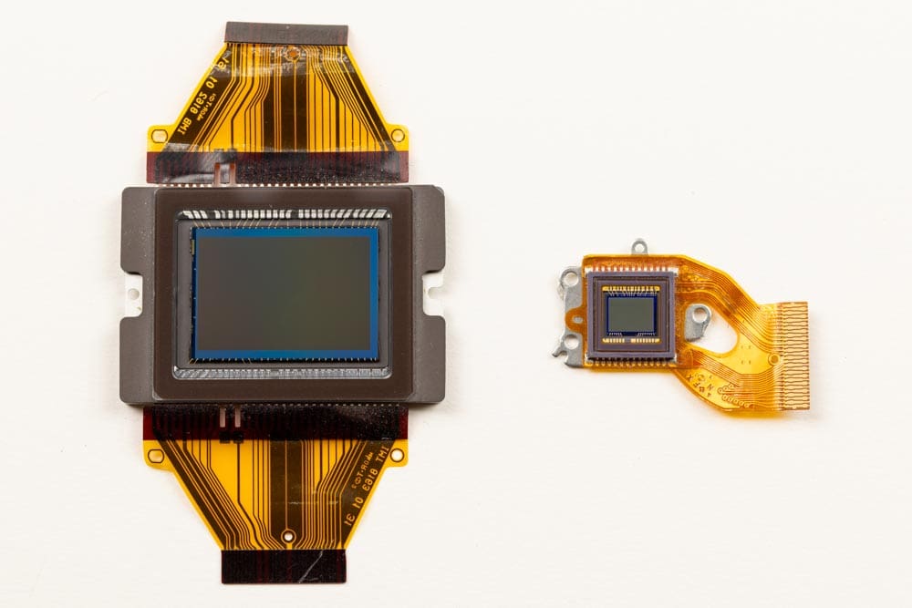 Two camera image sensors of different sizes displayed side by side on flexible circuit ribbons.